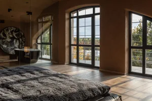 Luxurious, dark-themed bedroom interior with large windows overlooking nature.