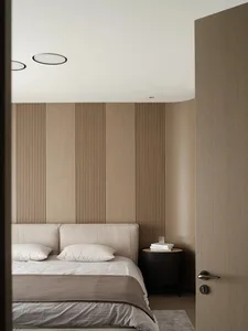A minimalist bedroom with a bed, pillows, and a nightstand with a glass and books.