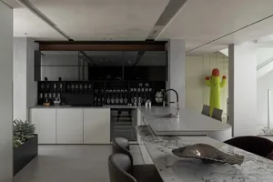 Modern minimalist kitchen with marble countertops and concrete base cabinets, featuring a sleek black backsplash and a built-