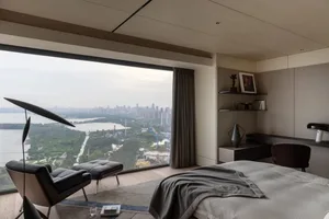 A modern minimalist living room with a large glass window showing a cityscape view.
