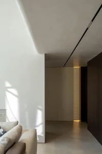 Modern residential corridor featuring concrete flooring and lighting details.