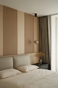 A minimalist bedroom featuring a wooden wall, potted plants, and a hanging pendant light.