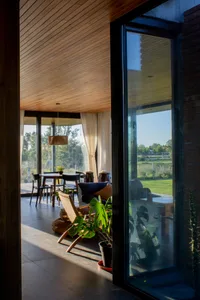 A minimalist living room with wooden flooring, glass sliding doors, and a comfortable seating area.