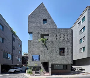 A modern brick building with a unique, angular design in an urban setting.