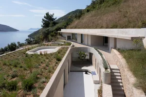 A modern house with a concrete exterior on a hillside.