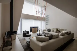 A modern living room with a concrete fireplace, a large U-shaped sofa, and a unique lighting fixture.