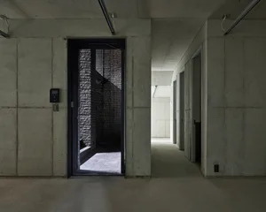 Minimalist concrete interior with a metal elevator and brick wall.