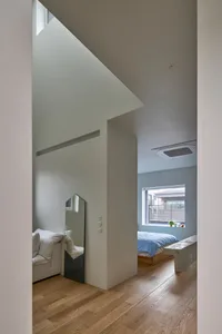 Modern minimalist bedroom with white walls and wood flooring.