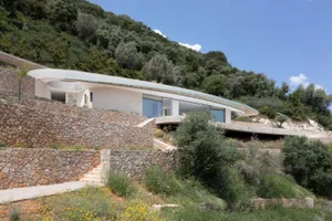 Modern residential house with concrete exterior on a grassy hillside