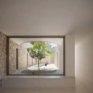 A modern interior design featuring a concrete floor and walls with a tree in the center.