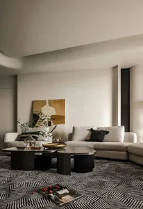 Modern living room with beige sectional sofa, patterned rug, and abstract art