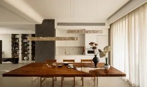 A modern residential kitchen with a wooden dining table and chairs, featuring a minimalist design with white cabinetry and a