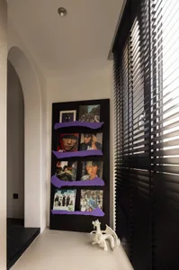 A minimalist black shelf display featuring books and framed pictures.