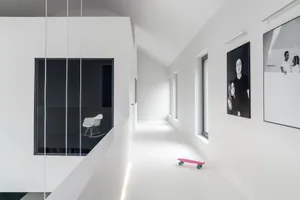 簡約風格的白色住宅走廊，擺放粉紅色滑板與裱框肖像畫。
