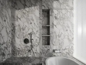 A modern bathroom featuring marble walls and a white bathtub.