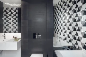 A modern bathroom featuring a black and white patterned tile wall, a walk-in shower, a white bathtub, and a floating white va