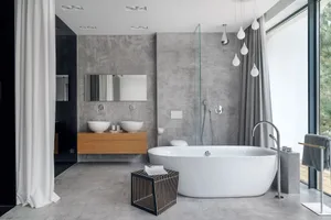 A modern minimalist bathroom featuring a freestanding bathtub, a floating vanity with dual sinks, and a concrete wall.