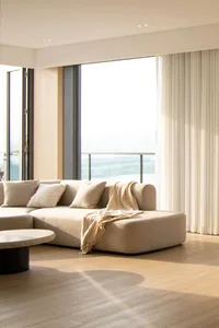 Modern, cozy living room with beige fabric furniture and large windows overlooking the outdoors.