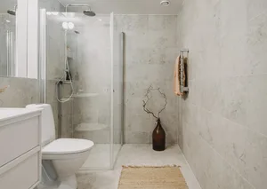 Modern minimalist bathroom with concrete tiles, glass shower enclosure, and white toilet.