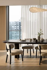 Modern dining room featuring a wooden table, fabric chairs, and minimalist design elements.