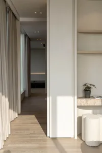 Minimalist interior space featuring light wood curtains on a window.