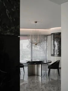 Modern dining room with black marble table and chairs, stainless steel base, and geometric chandelier