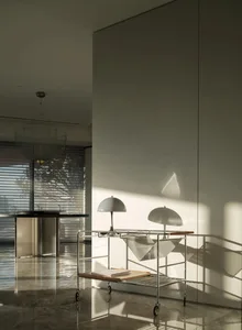 A modern interior featuring minimalist lighting fixtures with wire shades and glossy marble flooring, casting intricate shado