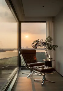 Modern living room featuring a brown leather chair and ottoman with a scenic view of the sunset through large windows.