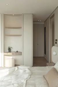 Modern minimalist bedroom featuring a white bed with neutral-toned bedding, wooden floating nightstands, and a large window w