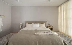 A modern minimalist bedroom with a white cotton bedspread and light-colored textiles.