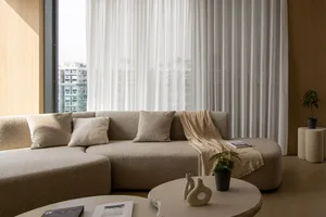 A modern, minimalist living room with a large, comfortable couch upholstered in neutral, textured fabric and accented with si