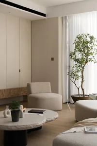 A modern living room featuring neutral-colored tiles and fabrics, with a large window, coffee tables, and potted plants.