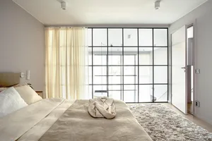Minimalist bedroom with a bed, window, and white and beige decor.