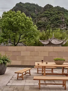 Outdoor seating area with wooden benches and tables overlooking lush greenery and mountains