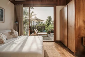Spacious minimalist bedroom with natural light, wood furnishings, and views of the exterior.