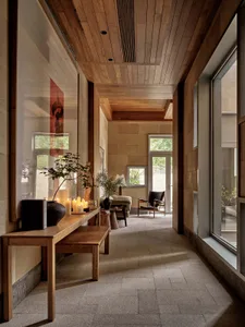 A modern corridor with wooden walls, ceiling, and floor, featuring wooden furniture and decor.