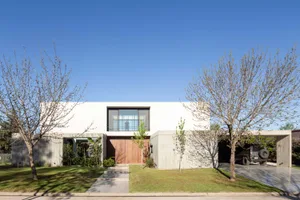 Clean modern house exterior with concrete facade and large windows.