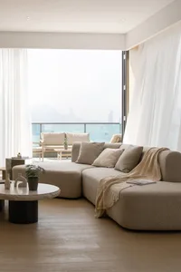 Modern living room with a contemporary fabric sofa, round coffee table, and floor-to-ceiling windows overlooking a scenic vie