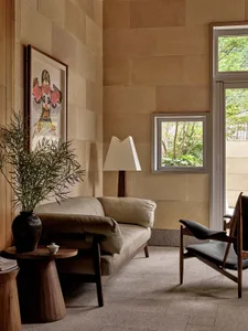 Modern living room featuring a couch, wooden chair, and framed artwork.