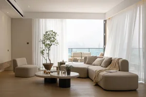 A modern living room with textured fabric furniture, large windows, and a view of the cityscape.