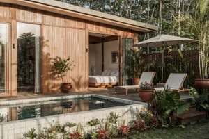 Modern minimalist house with an outdoor pool and lounge area, featuring wood siding, glass walls, and stone accents.