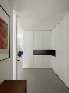 A minimalist kitchen with white cabinetry and a black countertop.