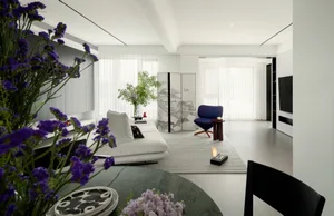Modern living room featuring a mix of white, blue, and purple decorative elements, including a white sofa, blue armchair, and