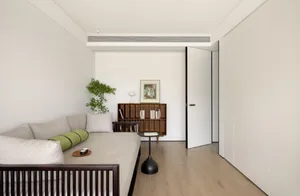 A modern minimalist living room featuring a comfortable sofa, a wooden coffee table, and a sleek metal bookshelf.