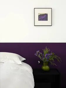 A bedroom with a purple panel wall and a white bed.