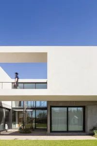 A modern house with a concrete exterior, featuring a balcony and large windows.