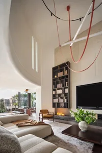 Modern living room with concrete walls and floor, featuring a tall bookshelf and a fireplace.