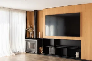 A modern living room featuring wooden panels, a flat-screen TV, and a fireplace.