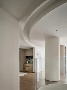 A modern, minimalist kitchen with white marble countertops and wooden cabinets.