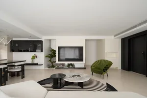 Modern living room with concrete floor, minimalist decor, and a green accent chair.